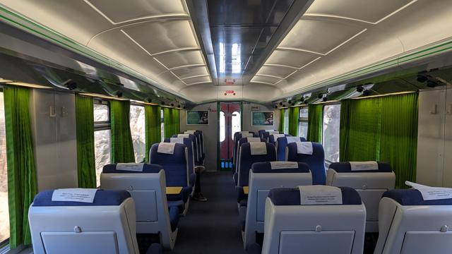 Interior of the coach, 2+1 configuration, white plastic seatshells, blue seat covers, green curtains