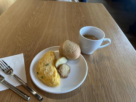Teller, mit kleinen Ei-Omelett, zwei halben Kartöffelchen und einem doppelten Espresso.