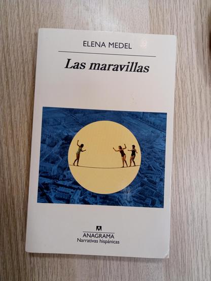 Las maravillas, de Elena Medel, publicado por Anagrama. La ilustración de la cubierta muestra a tres mujeres equilibristas de estilo clásico, una avanzando en dirección a las otras, sobre un fondo crema que simula un sol superpuesto a la imagen aérea de una ciudad velada en azul cobalto.