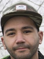 Foto van Nabille met glimlach, camouflage-petje en stoppelbaardje