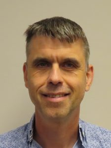 Foto van Kees, kort, licht-grijzend haar en een blauw-wit overhemd.