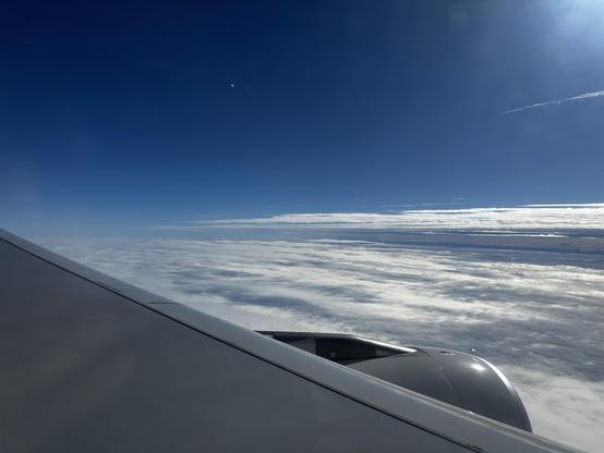 Über den Wolken, blauer Himmel und unter mir, das Wolkenmeer.
Im Vordergrund ein Teil des Flügels und ein wenig Triebwerk.