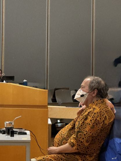 Richard Stallman sitting and wearing a mask