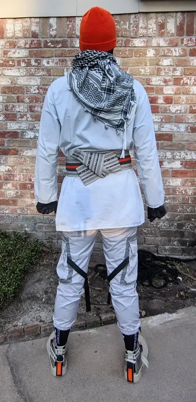 Back shot of me wearing an orange beanie, black and white checkered keffiyeh, white kurta shirt, black and white kaku obi with orange belt over it, white techwear style pants and white sneakers with orange LED lights on the heels.