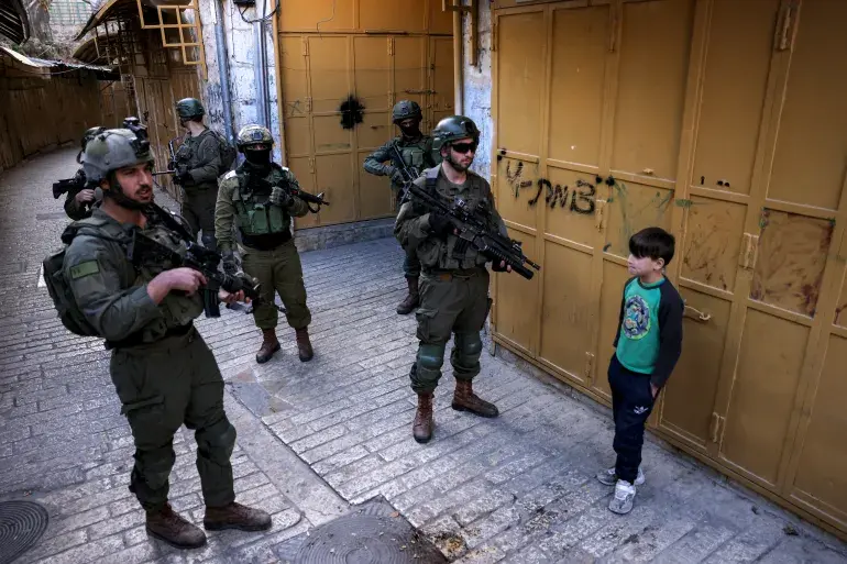 A Palestinian child and Israeli soldiers in Hebron.