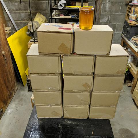 14 cardboard boxes that contain 4 jars each of honey and 1 jar of honey on top of the boxes.