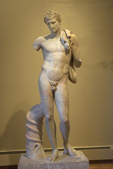 Marble sculpture of Hermes Chthonios, Hermes of the Underworld, perhaps representing a syncretism of Hermes in his Underworld aspect with a deceased individual who has been heroized. The god is in the nude with only a himation draped over his left shoulder. There is a tree trunk with a snake coiling around it to his right.