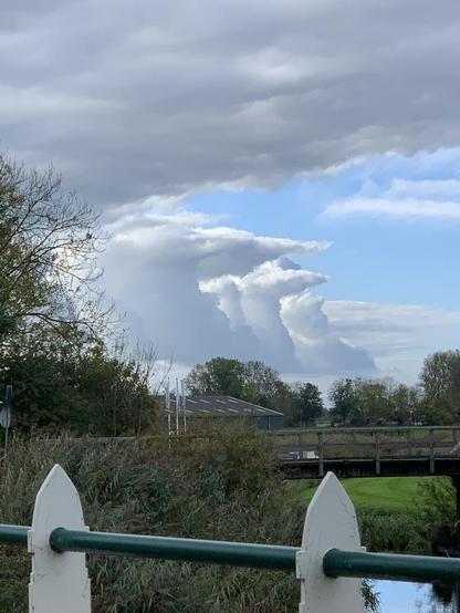 Hekje landschap en daarachter een rijtje rare puntige wolken als soldaten op appel.