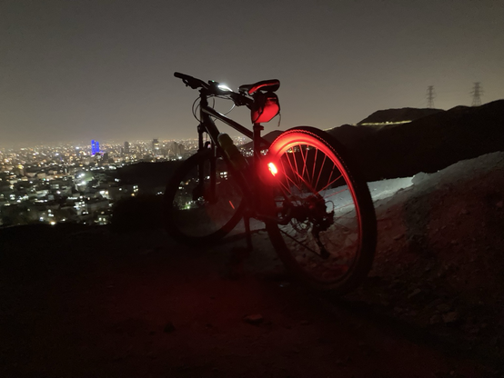 دوچرخه ای در شب از بالای کوه با منظره شهر