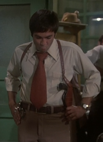 Gomez, with a wide tie & a gun.