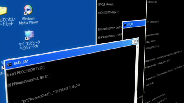 A computer screen seen close up with a few Windows XP icons on a desktop and windows of command prompt type windows.