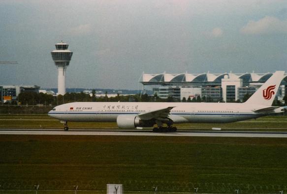 Viewed from the side, a white plane with red and blue details, rolls on an airport runway.