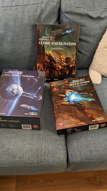 Three game boxes on a couch. Space Empires 4X Close Encounters, Space Empires 4X All Good Things, and Space Empires 4X Replicators.

All have sci-fi ship scenes on the front.