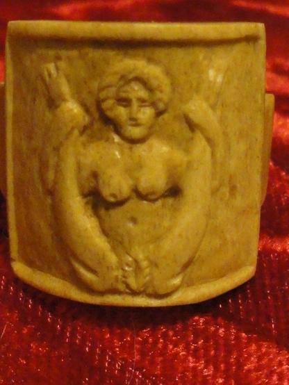 A relief of Baubo in the nude, pulling up her legs to expose her bushy vulva. She also has a nice pair of tits. Baubo flashed her vulva to Demeter when her daughter Persephone was missing to cheer her up and make her laugh.