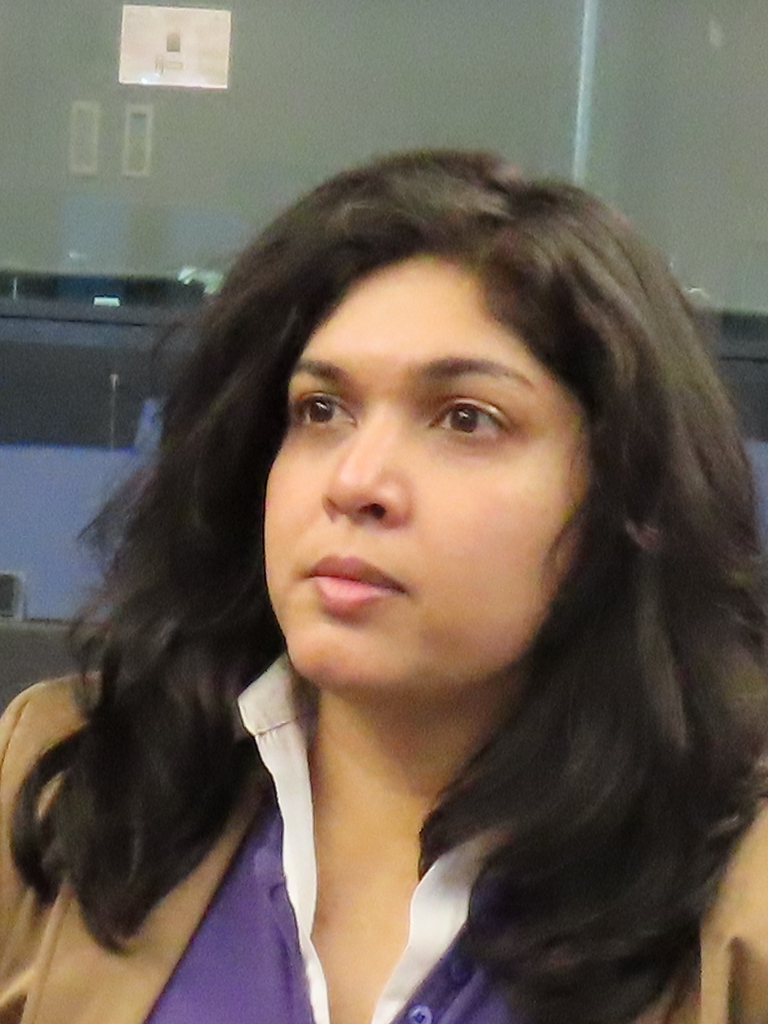 Foto van Saira, lange, zwarte haren, beige jasje, paars met wit bloesje