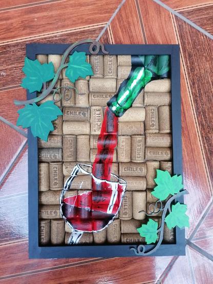 Cuadro hecho de corchos en los que está dibujada una botella virtiendo vino sobre una copa