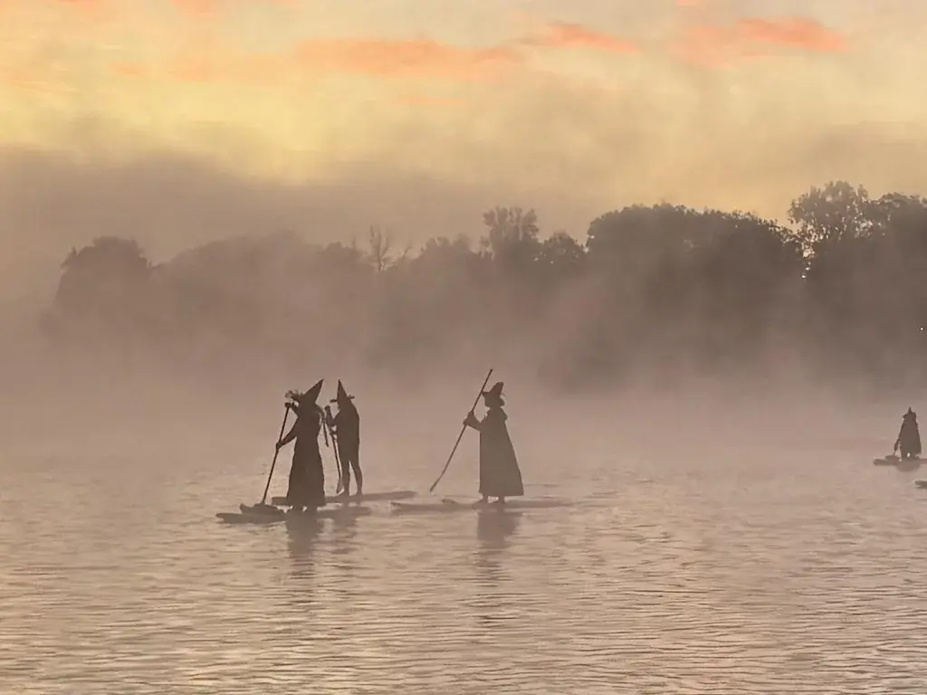 3 witches paddleboarding on a misty lake