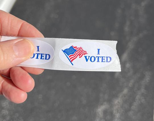 an “I voted” sticker held in a person’s hand