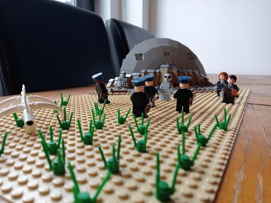 Some LEGO cops facing a UFO survivor with rifles, Mulder and Scully standing by to negotiate, crashed UFO in the background