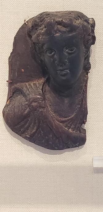 Very few ancient Greek works in wood have survived. This roundel presumably served as a fulcrum (headrest on a kline), a type well-known in bronze. The youthful, feminized image of Dionysos is typical of Hellenistic representations of the God of Wine.