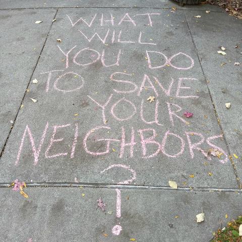 Chalk writing on a sidewalk: "What will you do to save your neighbors?"