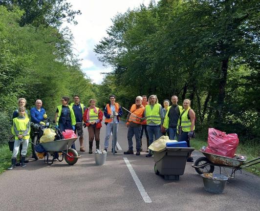 Un groupe de membres de l'association au milieu d'une route, habillés de gilets fluo, derière des brouettes chargées de détritus