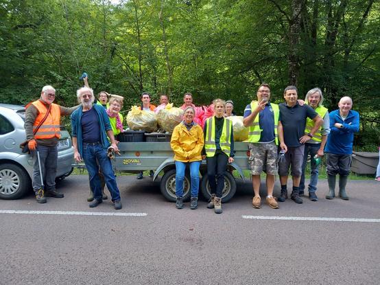 Un groupe de membres de l'association au milieu d'une route, habillés de gilets fluo, devant une remorque chargée de détritus