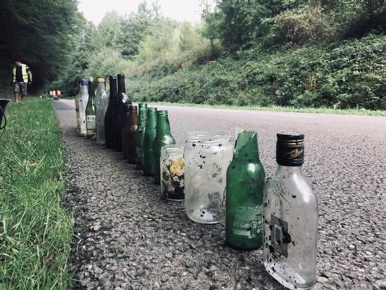 un alignement de bouteilles et pots en verre posé au bord d'une route
