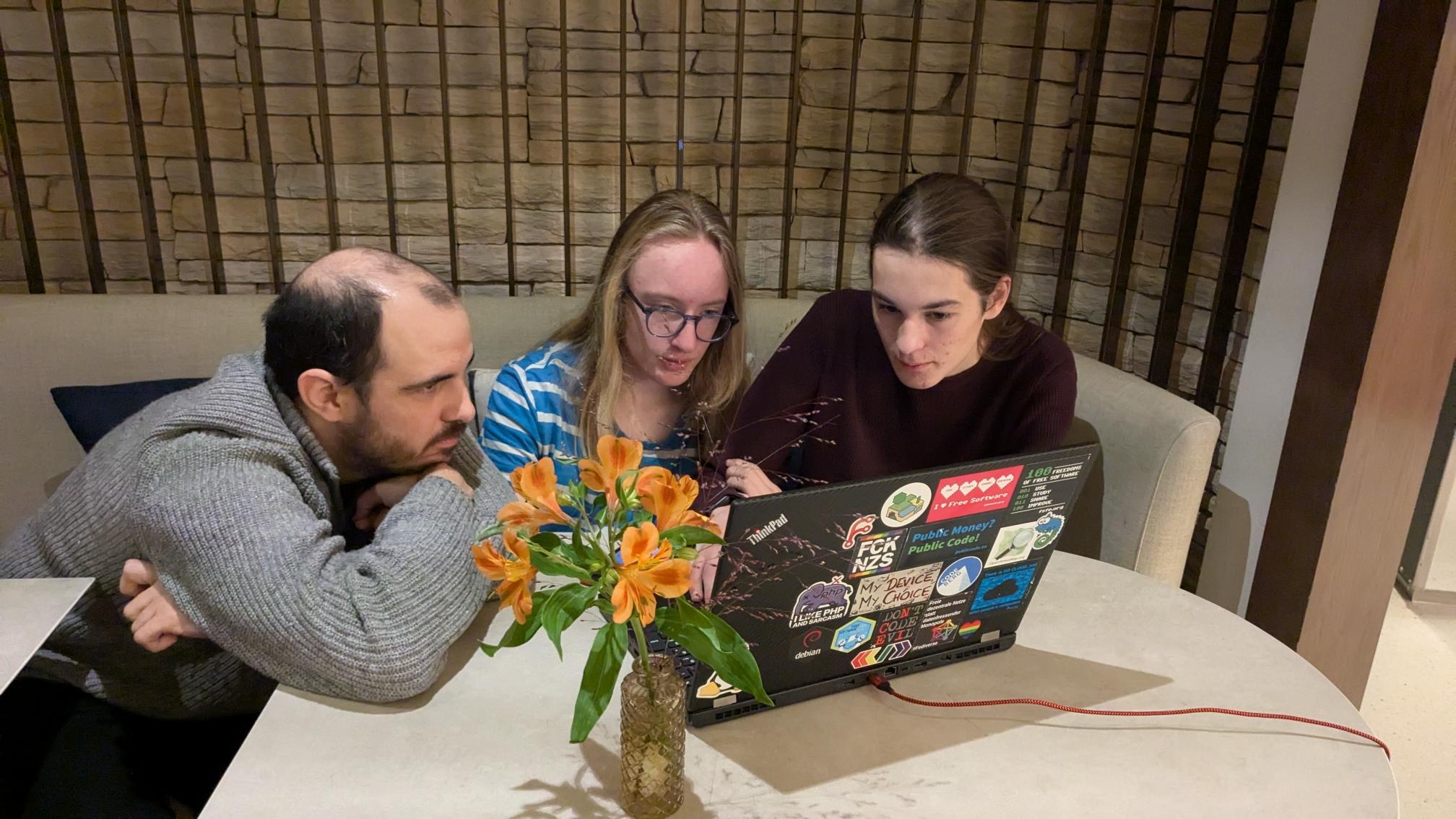 three people at a table with laptop