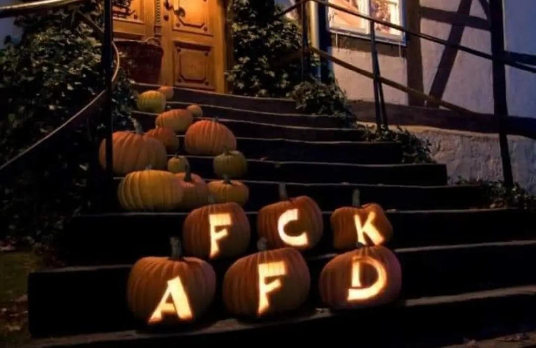Leuchtende Kürbisse vor einer Haustür, eingeritzt ist "Fuck AfD".