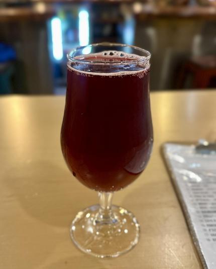 Ein Glas weinrotes Bier mit dünner Krone