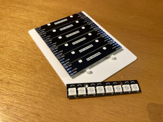 A bunch of NeoPixel strips in a 3D printed jig ready for soldering together.