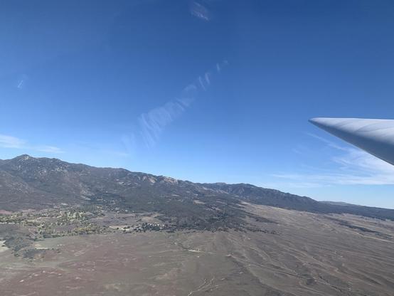 Mountains on a sunny day, and the wing of a glider in flight