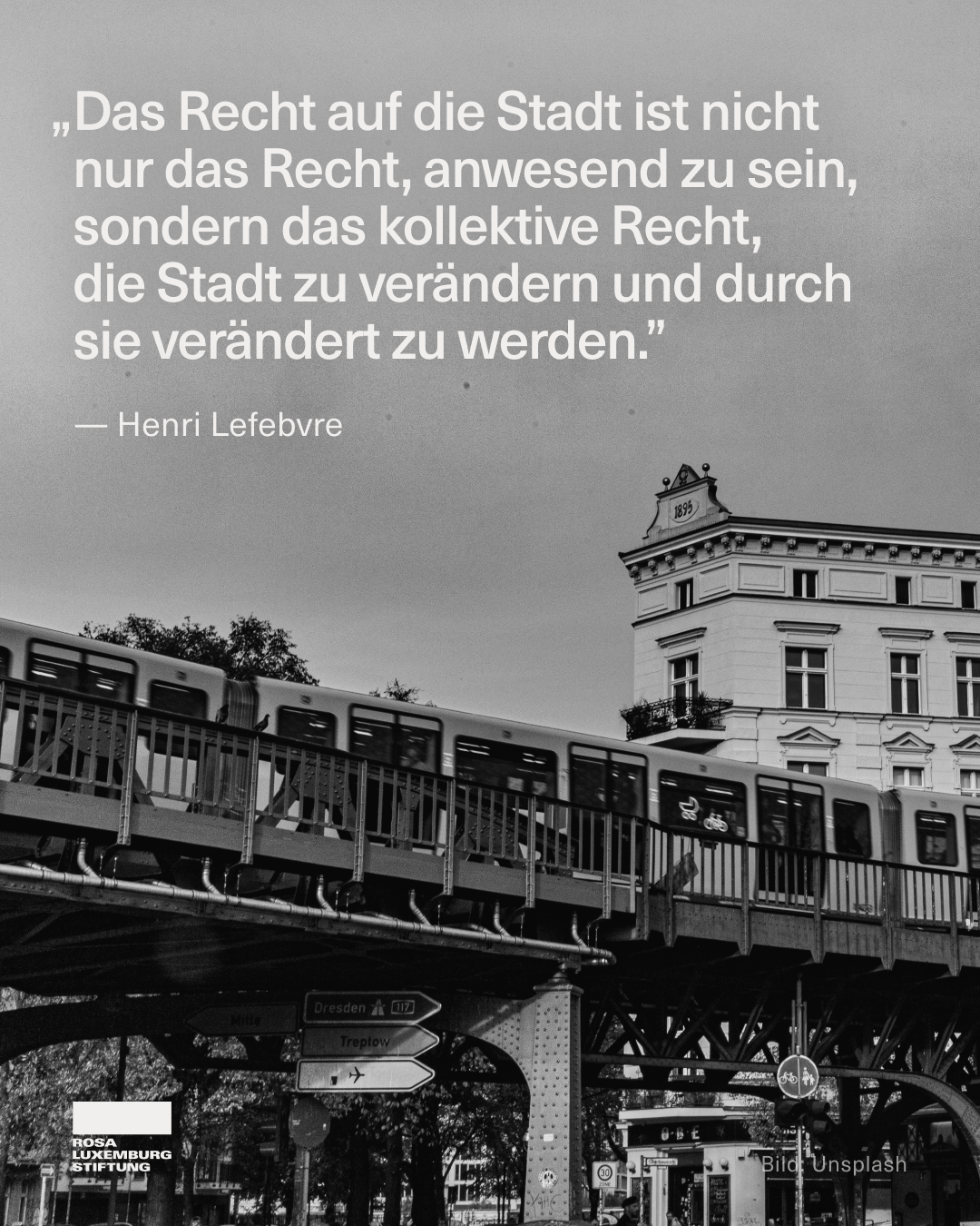 Das Bild zeigt ein schwarz-weißes Foto einer Stadtansicht. Im Vordergrund fährt eine erhöhte U-Bahn über eine Brücke, darunter stehen Straßenschilder mit Richtungen nach „Dresden“, „Treptow“ und „Mitte“. Rechts steht ein mehrstöckiges Altbaugebäude. Im oberen Teil des Bildes ist ein Zitat von Henri Lefebvre zu lesen: „Das Recht auf die Stadt ist nicht nur das Recht, anwesend zu sein, sondern das kollektive Recht, die Stadt zu verändern und durch sie verändert zu werden.“