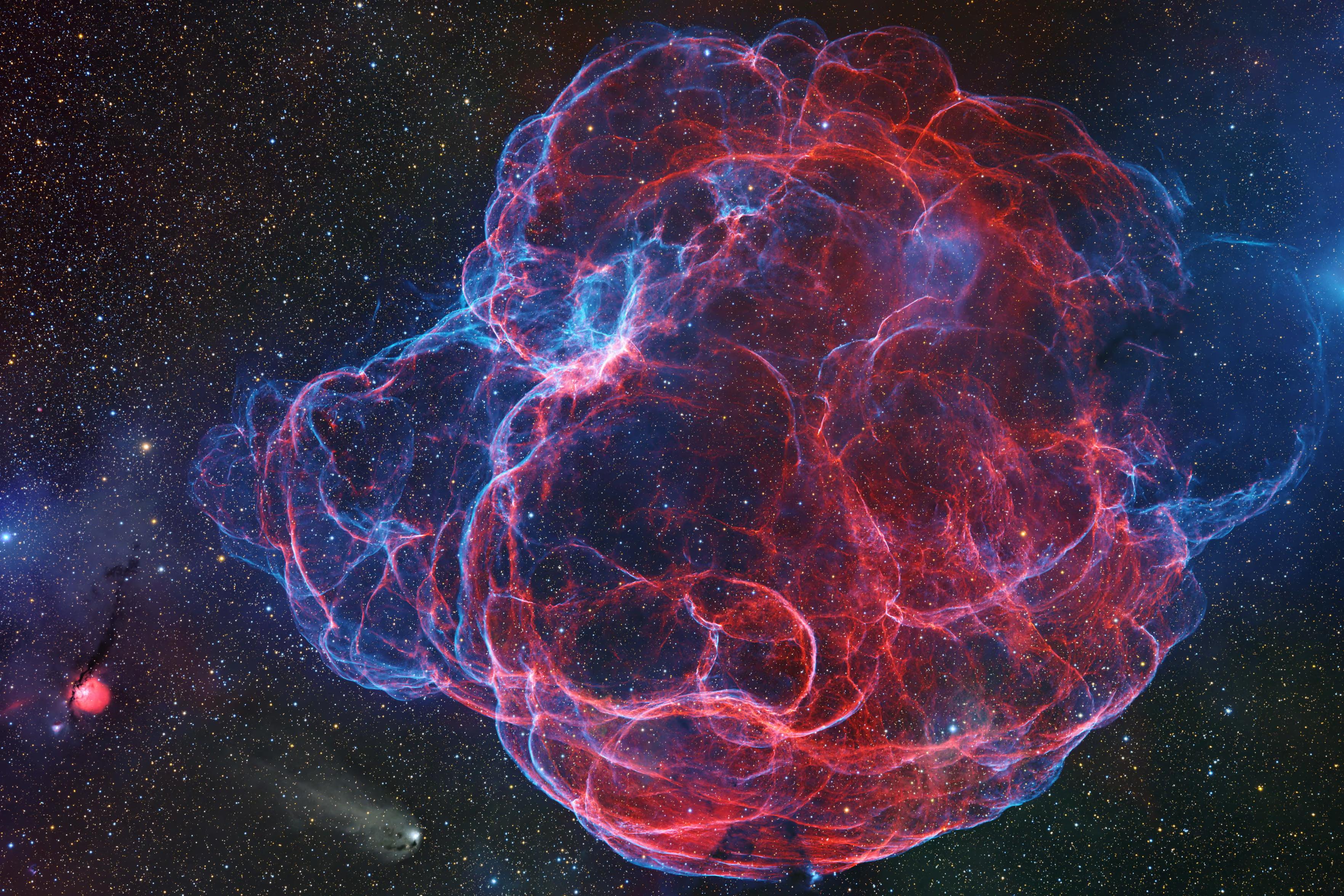 This full-spectrum image of the Spaghetti nebula unveils the faint and elusive nature of this supernova remnant, hidden behind a vast cloud of dust that obstructs its emission light. To enhance its visual appeal, Shaoyu Zhang dedicated considerable time to intensifying the blue and green hues and achieving added depth.