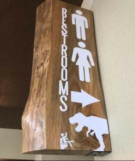 Picture of a restroom sign showing a male, a female, and a person sitting on the toilet while a T-rex attacks (from Jurassic Park)