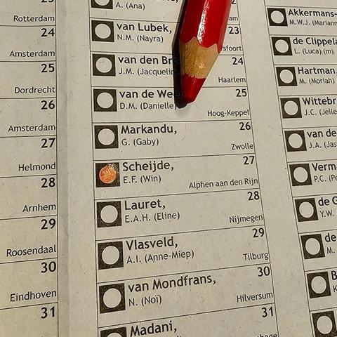 Close-upfoto van een stembiljet waarop met een rood potlood een vakje is ingekleurd. Het rood gemarkeerde vakje hoort bij kandidaat “Scheijde, E.F. (Win)” uit Alphen aan den Rijn. Boven het biljet ligt een rood potlood met een geslepen punt.