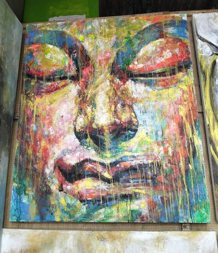a painting, it is a face, the eyes closed in meditation, prismatic tones coloring in his face, streaks of paint coming down like rain 
