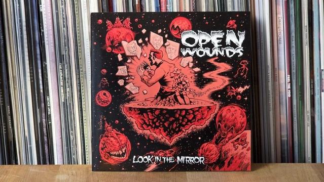 Das Bild zeigt das Albumcover „Look in the Mirror” von Open Wounds. Das Artwork zeigt eine zentrale Figur, umgeben von abstrakten, kosmischen Elementen, mit einem dunklen Hintergrund und leuchtend roten Akzenten. Es scheint zwischen verschiedenen Schallplatten platziert zu sein.
Übersetzt mit DeepL (https://dee.pl/app)