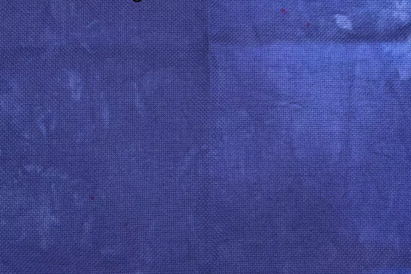A blue-purple fabric with a coupld of small dark pink specks on it.