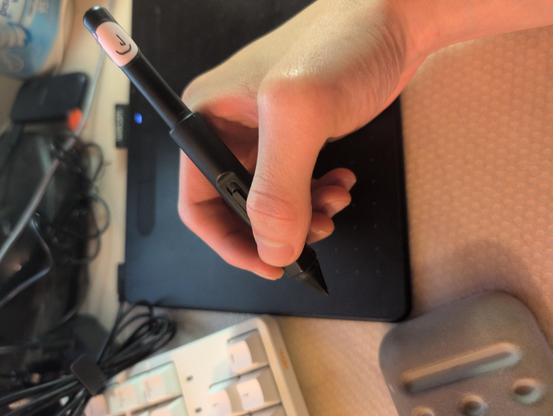 A hand holding a Wacom pen with pen grip.