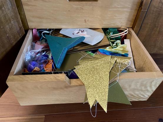 Een houten la die open staat en waar slingers en ballonnen in zitten