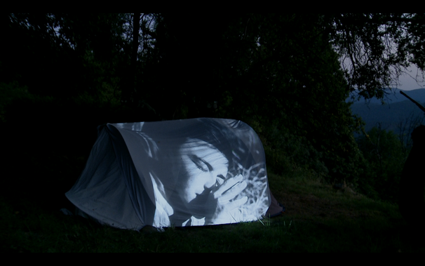 Photogramme issu d'Un café allongé à dormir debout, sur une toile de tente est projetée une séquence de "Moindre geste"