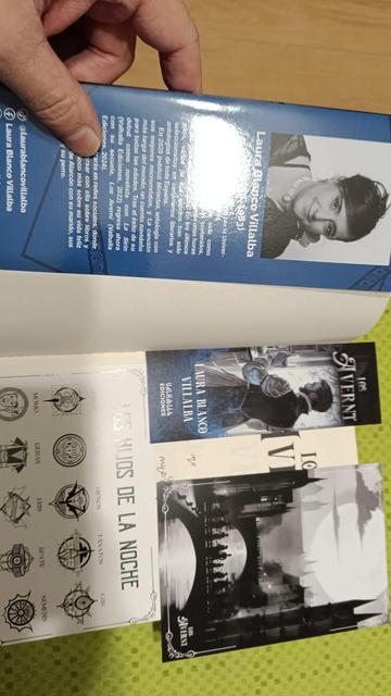 Solapa de «Los Averni», con una foto y la bio de la autora, Laura Blanco Villalba, junto con el marcapáginas, la ilustración del puente que hace de separación entre capítulos y otra tarjeta con las familias de vampiros de la novela.