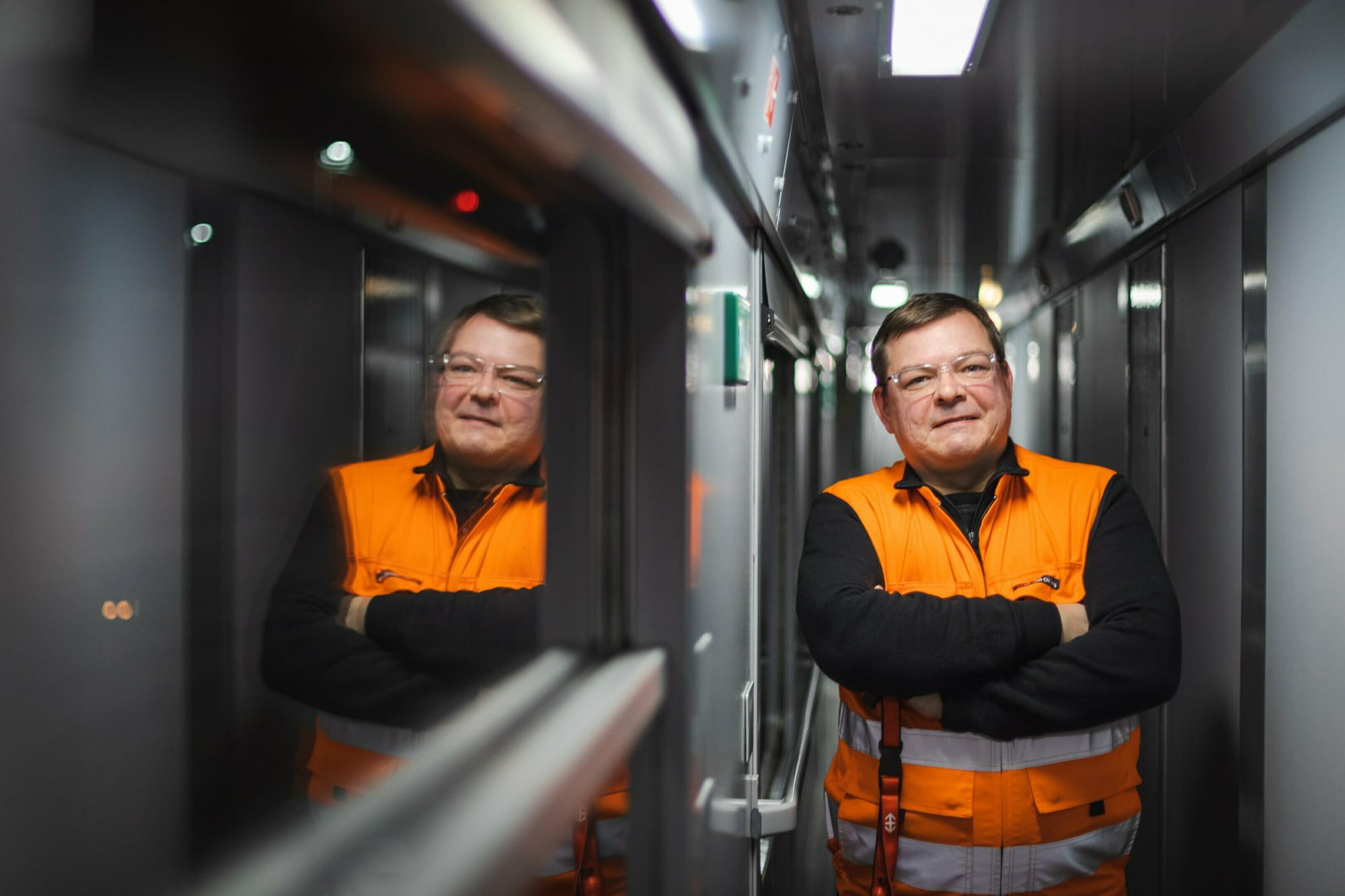 Mann mit Warnweste in einem Seitengang eines Eisenbahnwagens