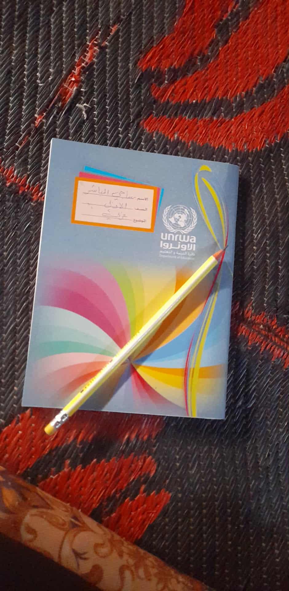 Picture of a UNRWA notebook and a pencil. Those are Saji's school supplies.