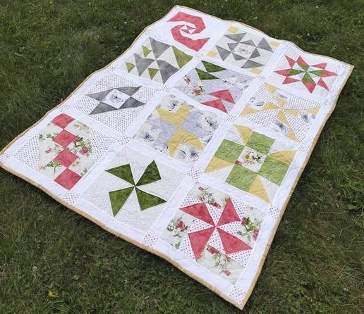 43 x 57 in (109 x 145 cm), a quilt, it is light coral red and yellow and grey shapes, each a different unique shape and design 