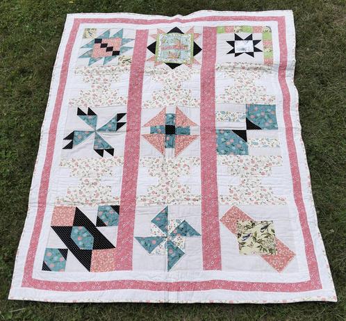 53 x 67 in (135 x 170 cm), a quilt, it is pink and florak patterns, blue as well and light naples yellow and some black, a thin pink border around it with a thin white border around that 
