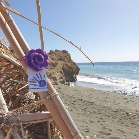 a purple crocheted rose on a beach in greece
