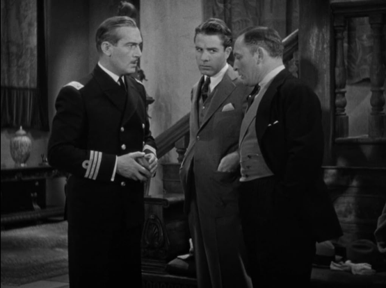 an image from the movie, it is several men standing and having a discussion in a parlor room, wearing suits in the style of the early 1930s